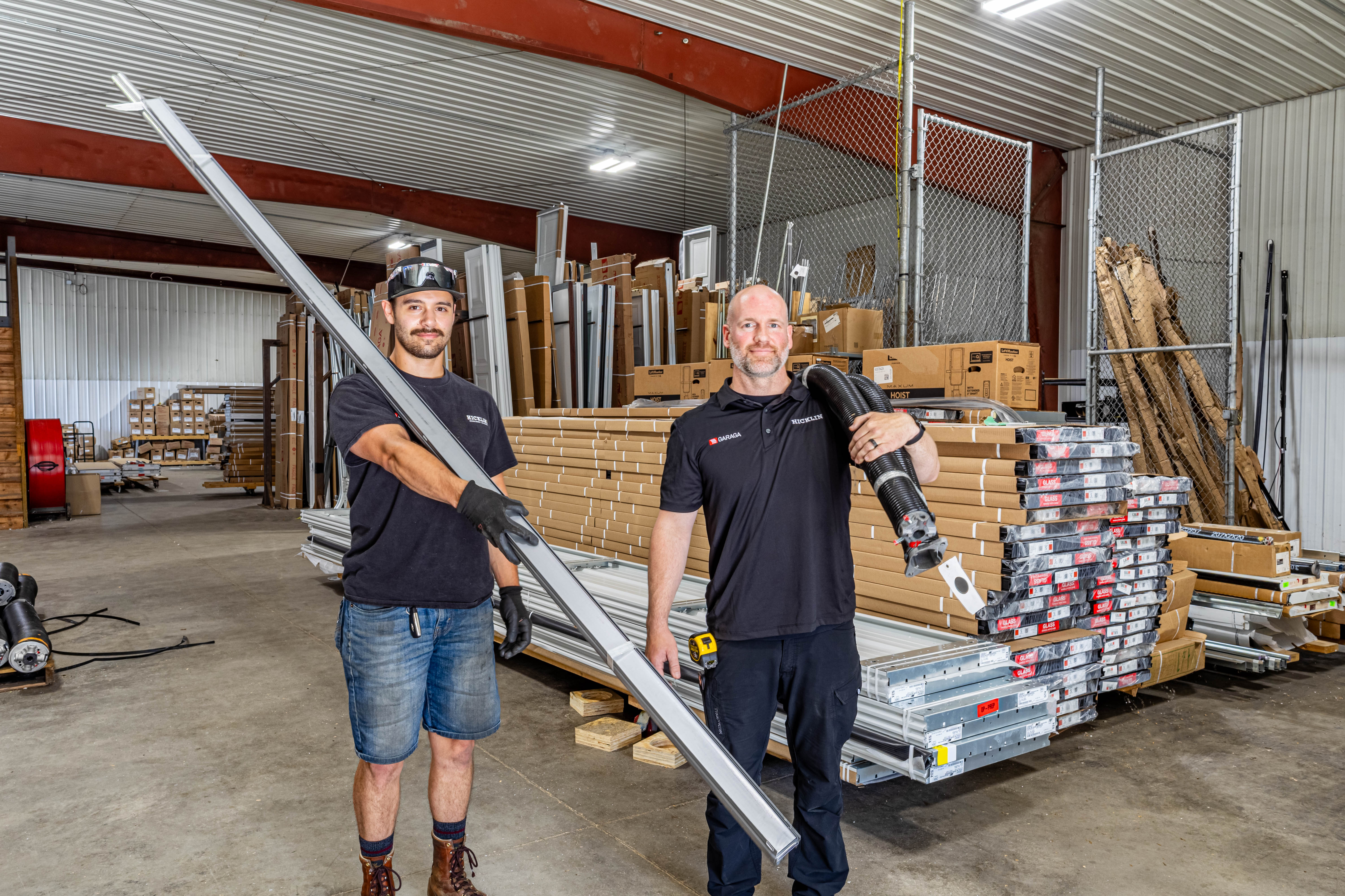 Two Hicklin Garage Door installers in warehouse with hardware in their hands